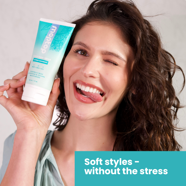 A woman holding a Curly Hair Cream bottle playfully