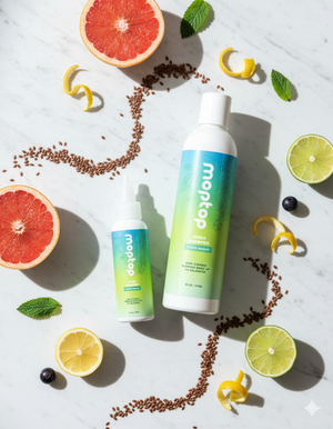 2 Bottles of Detox Shampoo surrounded by grapefruit and lime slices, citrus rind, seeds, black olives, and mint leaves