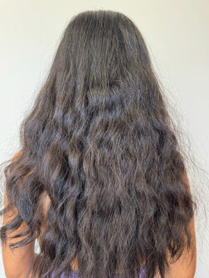 Back view of a woman with unstyled curly hair.