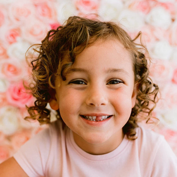 A kid smiling with curly hair